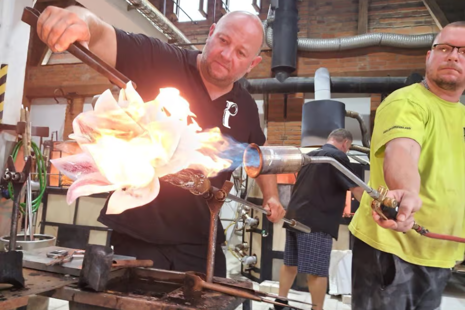 Two craftsmen work glowing molten glass amid the fiery beauty of Crystal Valley, Czech Republic.