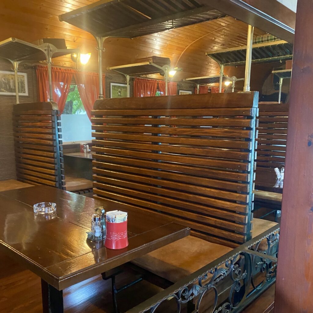 Interior of Balkan Express in Belgrade with wooden train-style booths, red curtains, and vintage railway decor.