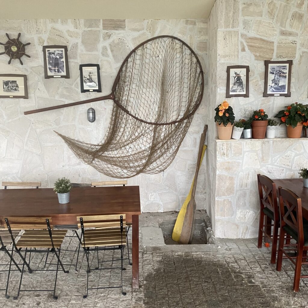 Interior of Radecki Club in Belgrade with a fishing net, wooden paddle, stone walls, and riverside restaurant decor.
