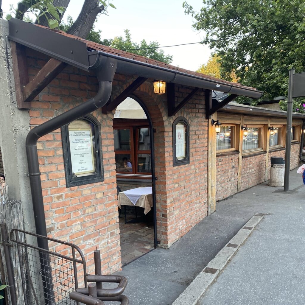 Exterior of Šabački Slatinac, a traditional Serbian kafana in Belgrade with brick walls and outdoor seating.