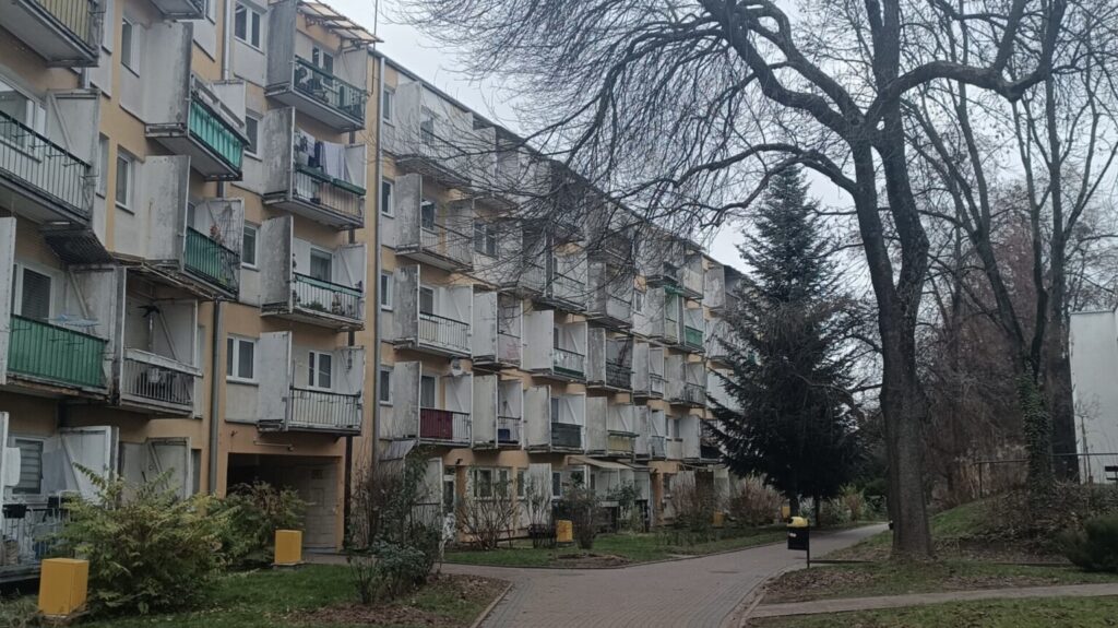 Apartment blocks, balconies, mature trees, and pedestrian paths at Osiedle Słowackiego in Lublin.